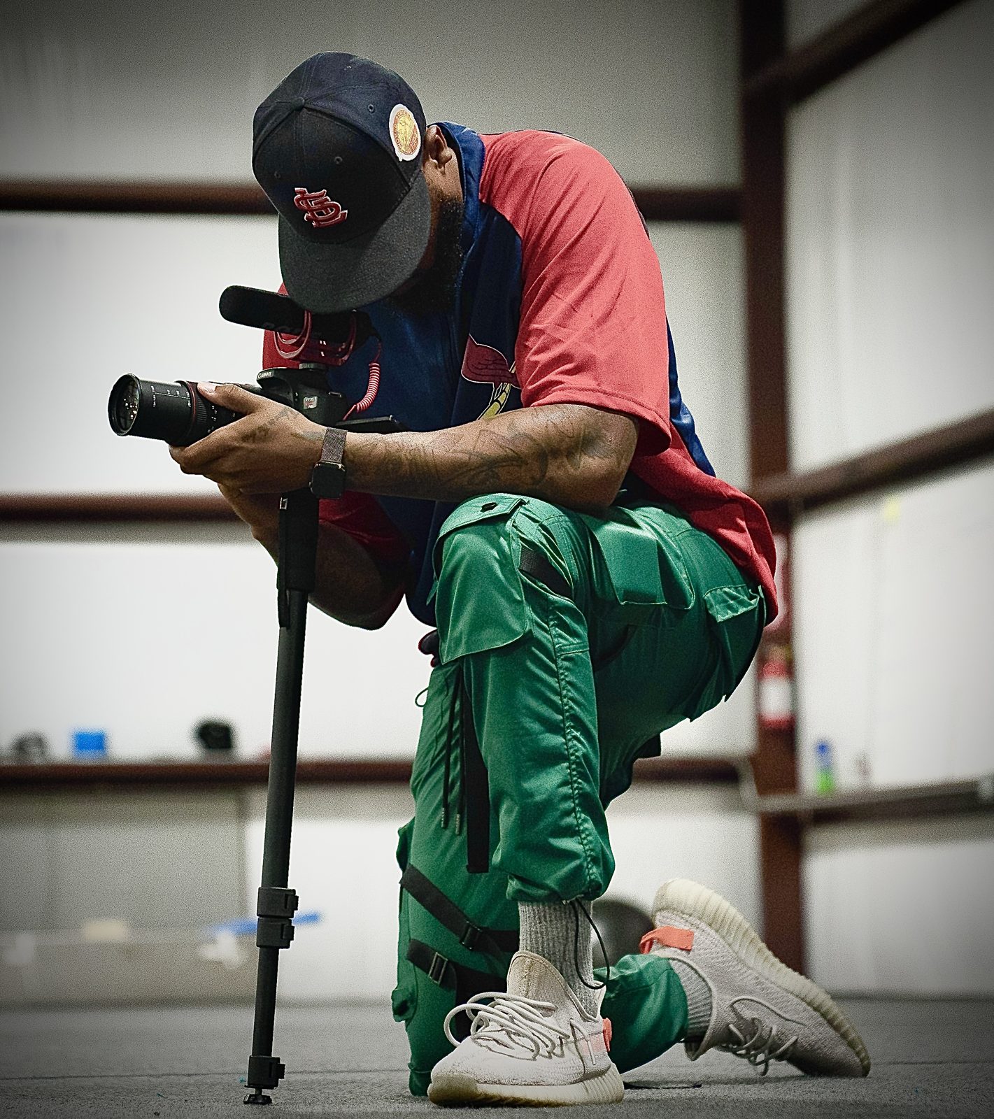 Nick Graves kneeling on set, framing a shot on a monopod-mounted camera